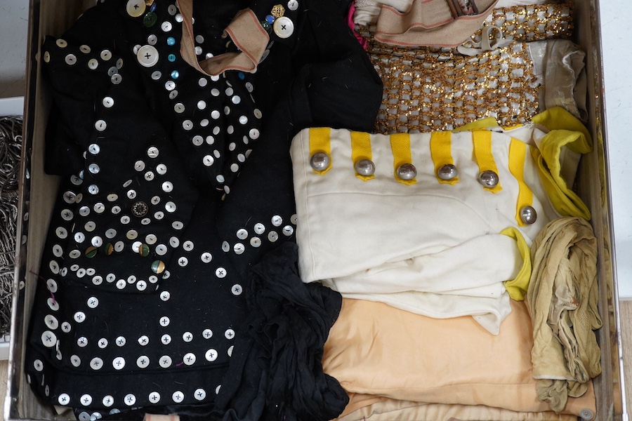 Two trunks containing a collection of children’s fancy dress from early 20th century, including an unusual child’s ‘pearly king’ suit, two earlier stockinette hats, a length of long silver metal fringing, ribboning etc.,